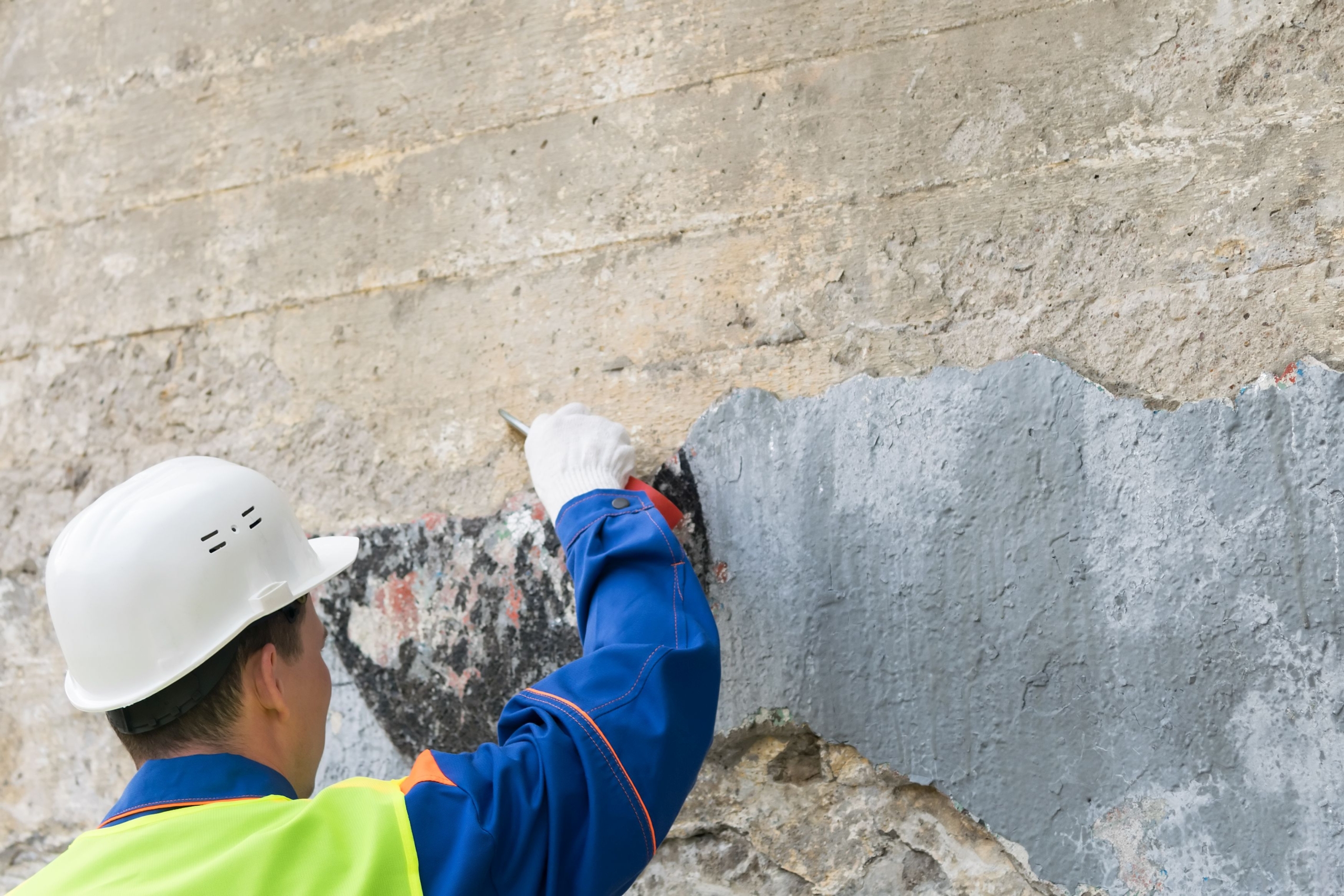 Mann mit Helm entfernt Graffiti