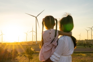 Mutter mit Kind schauen auf ein Feld mit Windrädern