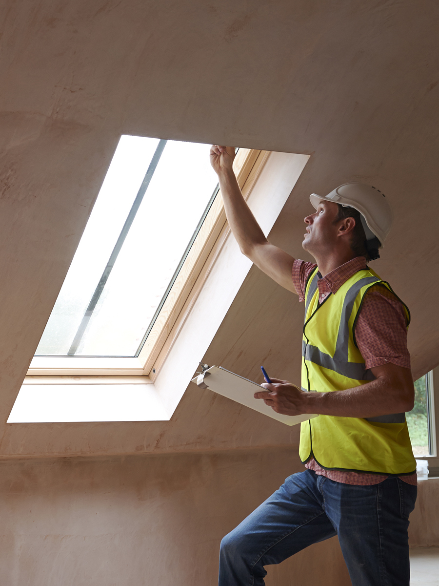 Mann mit Bauhelm kontrolliert Fenster